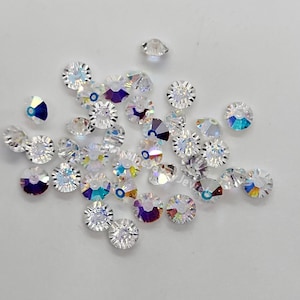 May include: A collection of clear crystal beads with iridescent facets. The beads are round and have a faceted design.