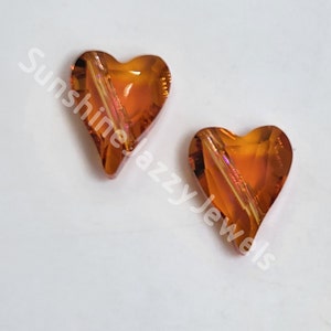 May include: Two amber heart-shaped glass beads with a clear iridescent finish.