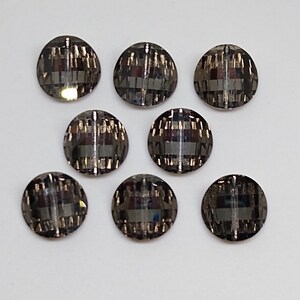 May include: Eight round, black and silver, iridescent, decorative buttons with a geometric pattern.