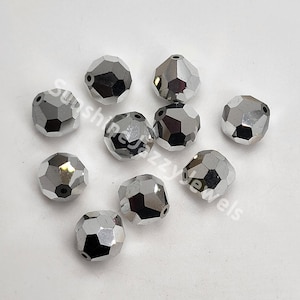 May include: Ten silver faceted glass beads. The beads are round and have a shiny finish.