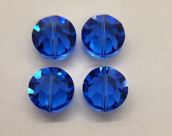 May include: Four round, faceted, blue glass beads with a hole through the center.