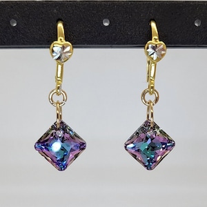 May include: A pair of gold earrings with a heart-shaped clasp and a square-shaped iridescent gemstone pendant.