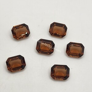 May include: Six faceted, rectangular gemstones with a warm, amber hue. The gems have a dark brown border and a polished, reflective surface. The text "Sunshine Jazzy Jewels" is visible on the background.