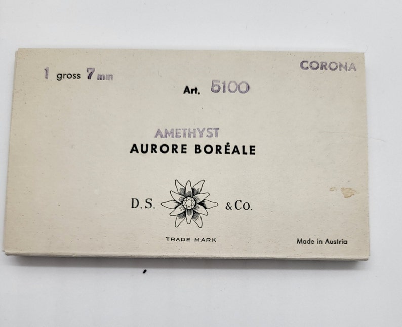 May include: A rectangular box with the text "CORONA" and "1 gross 7 mm." The box also features the text "Art. 5100," "AMETHYST AURORE BOR&Eacute;ALE," and "D.S. & Co. TRADE MARK Made in Austria."