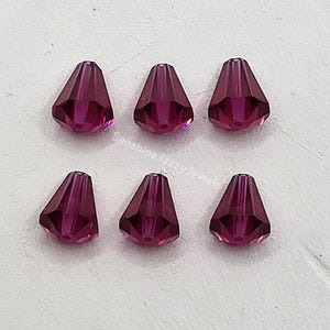 May include: Six deep purple crystal teardrop beads with a faceted design.