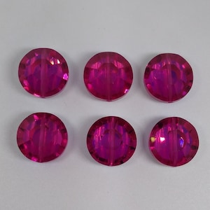 May include: Six round, iridescent pink glass beads. The beads have a faceted design and are approximately 1 cm in diameter.