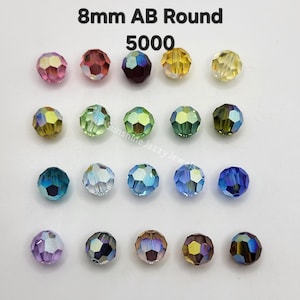 May include: A collection of twenty 8mm AB round faceted crystal beads arranged in a four-by-five grid. The beads feature a variety of iridescent colors including pink, red, dark purple, yellow, green, blue, and brown, all with a reflective finish.