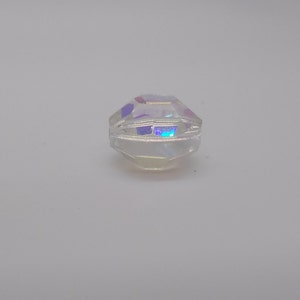 K&ouml;nnte beinhalten: Eine klare, irisierende Glasperle mit facettiertem Design.