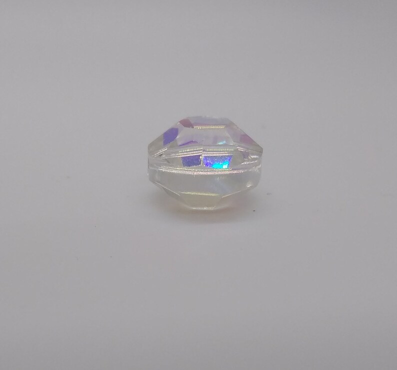 K&ouml;nnte beinhalten: Eine klare, irisierende Glasperle mit facettiertem Design.