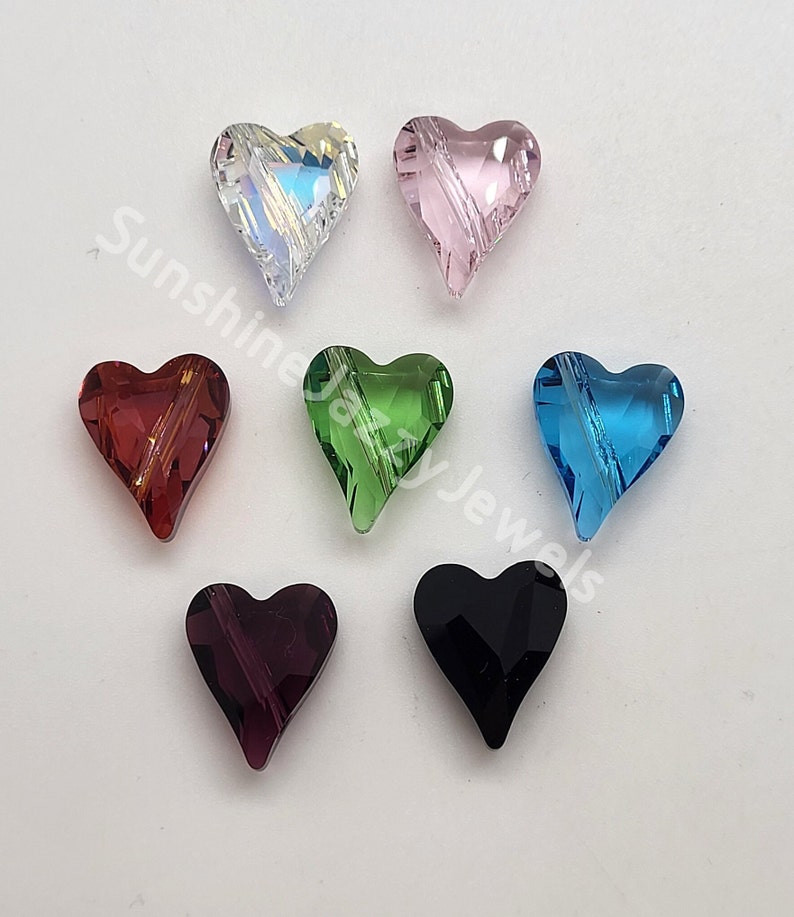May include: Seven heart-shaped crystal beads in various colors, including clear, pink, red, green, blue, purple, and black. The beads have a faceted design and are approximately 1 inch in size.