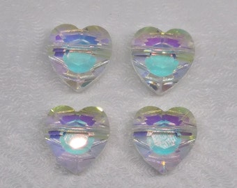 May include: Four iridescent heart-shaped glass beads with a rainbow effect. The beads are clear with a light blue center.