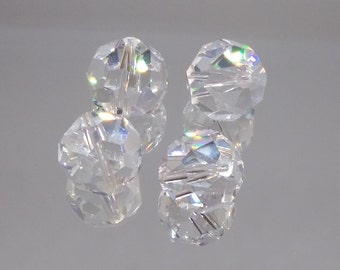 May include: Four clear glass beads with a faceted design. The beads have a rainbow iridescent effect.