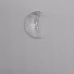 May include: A clear crystal crescent moon charm with a small hole at the top for hanging.