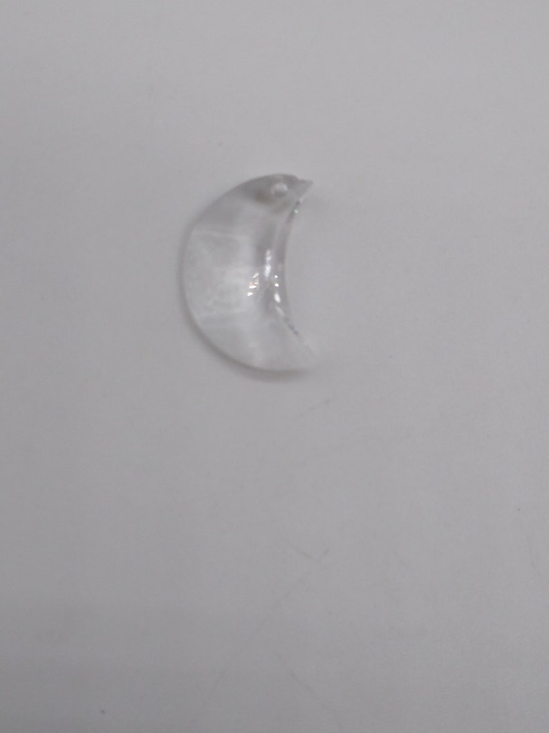 May include: A clear crystal crescent moon charm with a small hole at the top for hanging.