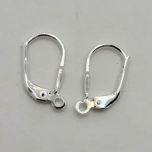 May include: Two silver-colored leverback earring findings. Each finding has a curved top, a hinged lever, and a small loop for attaching an earring. The findings are designed for secure earring closures.