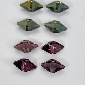 May include: Eight faceted glass beads in two colors. Four are a light green with a gold iridescent sheen, and four are a deep purple with a silver iridescent sheen.