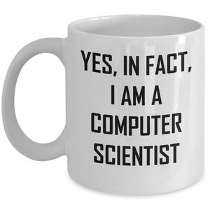 May include: White ceramic mug with a curved handle. The mug features the text "YES, IN FACT, I AM A COMPUTER SCIENTIST" in bold black letters. The mug is designed for hot beverages.