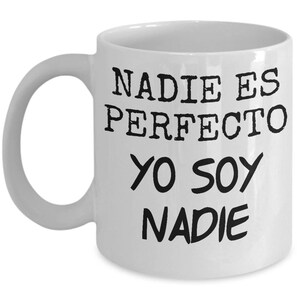 May include: White ceramic coffee mug with black text that reads "Nadie es perfecto yo soy nadie".