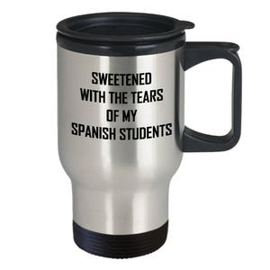 Puede incluir: Taza de viaje de acero inoxidable con tapa y asa negras. La taza tiene el texto "Sweetened with the tears of my Spanish students" impreso en ella.