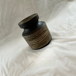 May include: A brown and white ceramic vase with a textured surface.