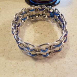 Peut inclure: Un bracelet argent&eacute; fait de languettes de tirage reli&eacute;es avec des accents bleus et violets.