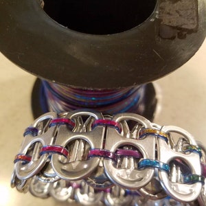 Peut inclure: Un bracelet argent&eacute; fait de languettes de canettes tiss&eacute;es ensemble avec du fil iridescent color&eacute;.