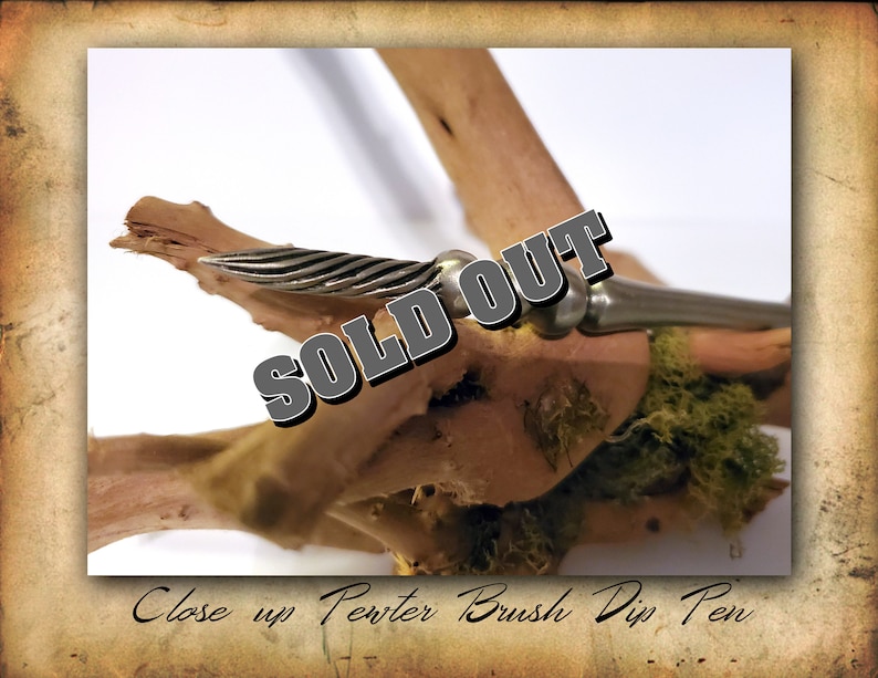 Puede incluir: Primer plano de una pluma de inmersi&oacute;n de pincel de plata que descansa sobre un trozo de madera a la deriva con musgo verde. La pluma tiene una punta de metal retorcida y un mango de plata. La imagen tiene el texto "SOLD OUT" sobre la pluma.