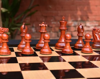 Op de afbeelding: Een houten schaakset met rode en bruine stukken op een houten schaakbord. De stukken zijn in de beginpositie voor een schaakspel gerangschikt.