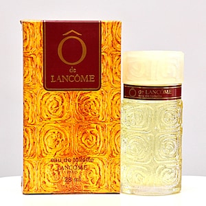 Può includere: Un flacone vintage di eau de toilette "Ô de Lancôme", con una scatola abbinata. Il flacone è trasparente con un design strutturato e la scatola è dorata con un motivo a rose. La scatola e il flacone presentano il logo e il testo Lancôme. Il flacone contiene 28 ml.