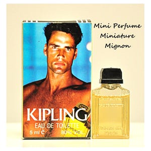 Può includere: Un flacone in miniatura di Kipling Eau de Toilette, 5 ml, con tappo nero, accanto a una scatola con l'immagine di un uomo. La scatola riporta il nome del marchio e i dettagli del prodotto. È visibile anche il testo "Mini Perfume Miniature Mignon".
