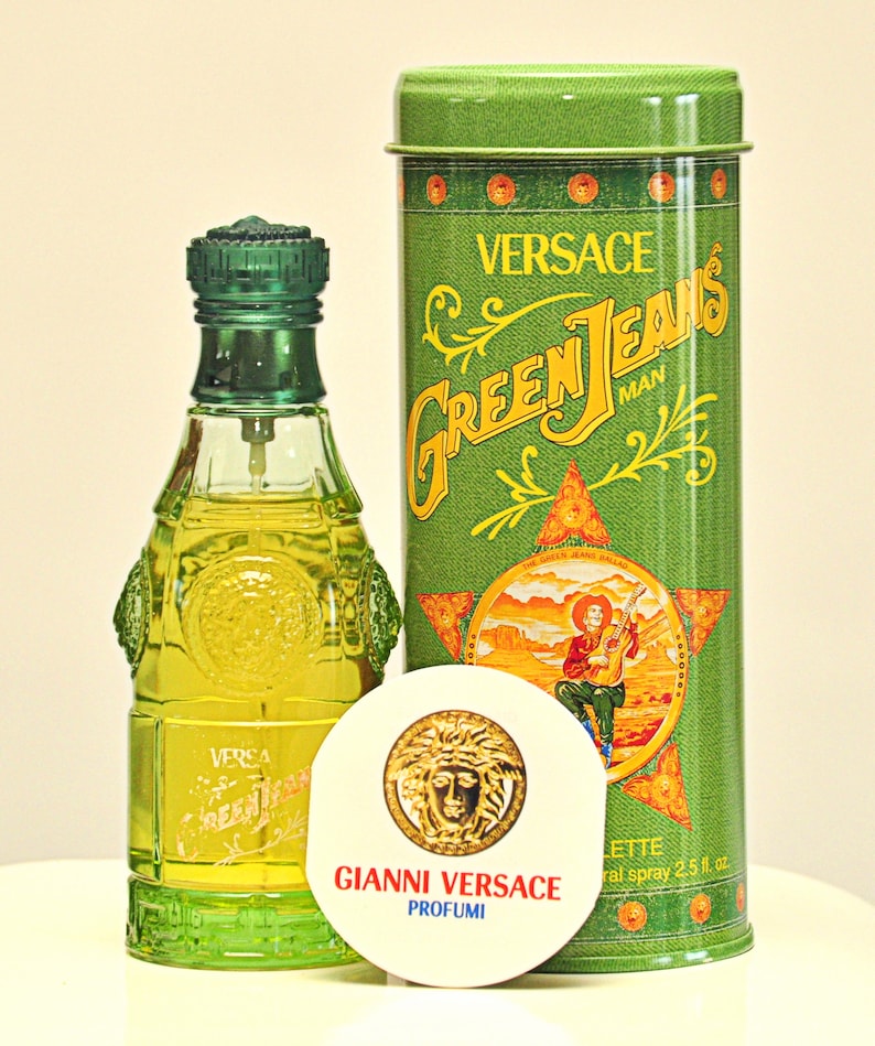 May include: A Versace Green Jeans Man fragrance set. The set includes a green glass perfume bottle, a green metal container, and a round white disc with the Versace logo. The container has the words "Green Jeans Man" in yellow.