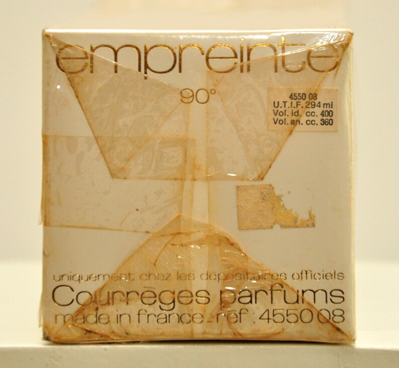 May include: A white box with gold lettering that reads "empreinte 90&deg;" and "Courreges parfums made in france - ref: 4550 08". The box also has a label with the text "4550 08 U.T.I.F. 294 ml Vol. id, cc. 400 Vol. an. cc. 360".