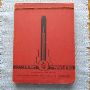 May include: A red book with the title "20th Century Typewriting" and the text "Complete Second Edition" and "South-Western Publishing Company". The book cover features a black and white stylized building.