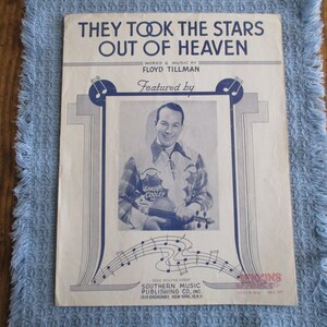 May include: Sheet music titled "They Took the Stars Out of Heaven" by Floyd Tillman, featuring Spade Cooley. The cover has a portrait of a smiling man holding a violin, with musical notes and decorative elements.
