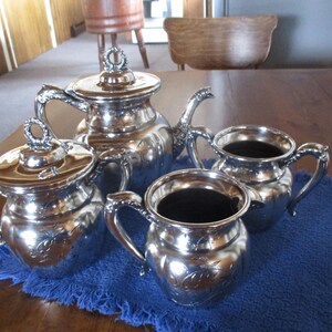 May include: A silver tea set with a teapot, creamer, and sugar bowl. The set has an ornate design with floral motifs.