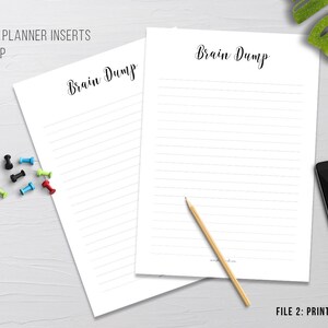 May include: Two white lined "Brain Dump" planner inserts with the text "Brain Dump" in a handwritten font. A pencil, push pins, a smartphone, and a small potted plant are also visible. The text "Printable Planner Inserts" and "File 2: Print on to A5 paper" are also visible.