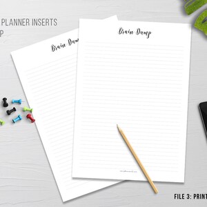 May include: Two white lined planner inserts with the text "Brain Dump" in a handwritten font. A pencil, push pins, a smartphone, and a potted plant are also visible. The text "Printable Planner Inserts" and "Files Included" are also visible.