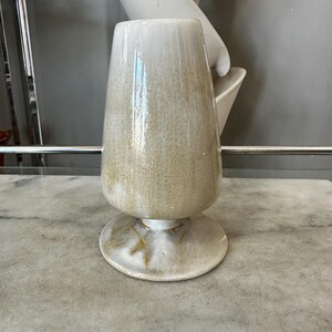 May include: A set of three ceramic mugs with a speckled, matte finish. The mugs are in shades of cream, light gray, and dark gray. Each mug has a simple, minimalist design and a rounded handle.