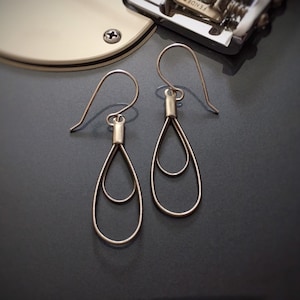 May include: A pair of silver teardrop earrings with a double-loop design.
