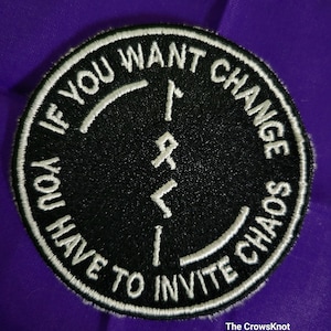 May include: Black embroidered patch with white stitching. The patch is round and features the text "If you want change you have to invite chaos" with a rune symbol in the center.