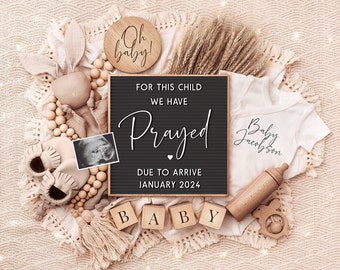May include: A black letter board with the text "For this child we have prayed. Due to arrive January 2024."  Surrounding the board are wooden blocks spelling "baby", a wooden rattle, a wooden bottle, a white onesie with the text "Baby Jacobson", a wooden sign with the text "Oh baby!" and a small ultrasound image.