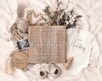 Könnte beinhalten: Ein Holz-Buchstabenbrett mit dem Text "A Tiny Gift for Christmas Arriving April 2023". Neben dem Buchstabenbrett liegt ein weißer Strampler mit dem Text "Baby Hendry". Im linken unteren Eck des Bildes befindet sich ein Holzschild mit dem Text "Coming Soon". Außerdem sind Holzperlen, ein kleiner Holzbaum und ein Paar Babyschuhe zu sehen.