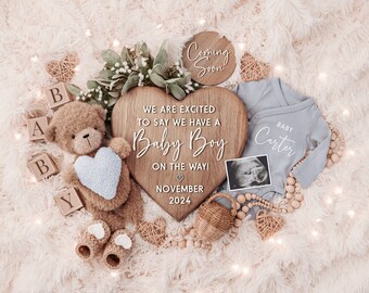 May include: A baby announcement with a wooden heart sign that says "We are excited to say we have a Baby Boy on the way! November 2024". There is a teddy bear holding a blue heart, a baby onesie that says "Baby Carter", and a wooden sign that says "Coming Soon".