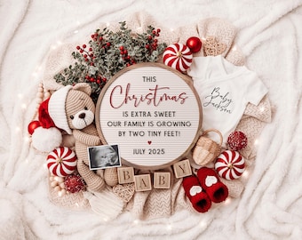 Könnte beinhalten: Eine weiße Buchstabentafel mit dem Text "This Christmas is extra sweet our family is growing by two tiny feet! July 2025". Die Tafel ist umgeben von roten und weißen Zuckerstangen, einem Teddybär, einem Baby-Strampler mit dem Text "Baby Jackson" und einem kleinen Holzkörbchen.