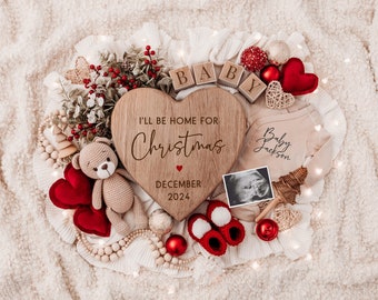 May include: A wooden heart-shaped sign with the text "I'll be home for Christmas" and the date "December 2024". The sign is surrounded by red hearts, a teddy bear, a baby onesie, a sonogram photo, and Christmas decorations.