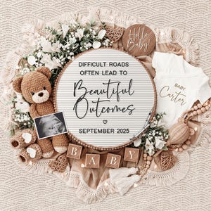 May include: A white letter board with the text "Difficult roads often lead to beautiful outcomes" and the date "September 2025". The board is surrounded by a teddy bear, baby booties, a baby onesie, and wooden blocks that spell out "BABY".