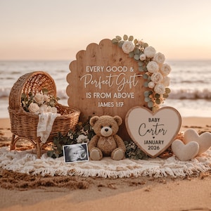 May include: A beach scene with a wicker baby carriage filled with flowers, a teddy bear, and a sign that reads "Baby Carter January 2026." The sign is heart-shaped and surrounded by two heart-shaped pillows. The background includes the ocean and a wooden sign with text.