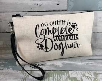 May include: A white canvas zippered pouch with a black strap. The pouch has black text that reads "no outfit is complete without dog hair".