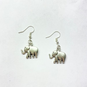May include: A pair of silver elephant dangle earrings. The elephants are facing to the right and have a detailed design.