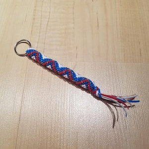 May include: A red, white, and blue braided keychain with a silver key ring.